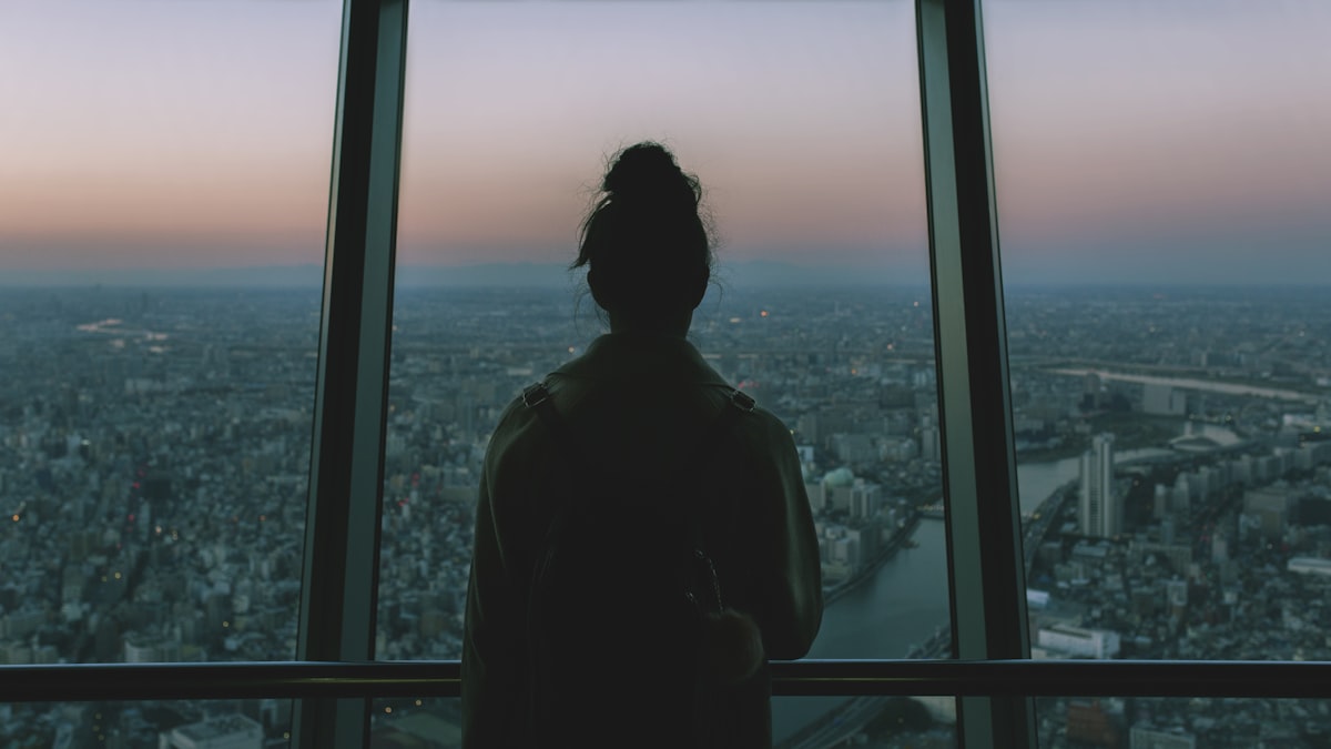 Silhouette reflecting at a city window at dusk — auditing your money mindset